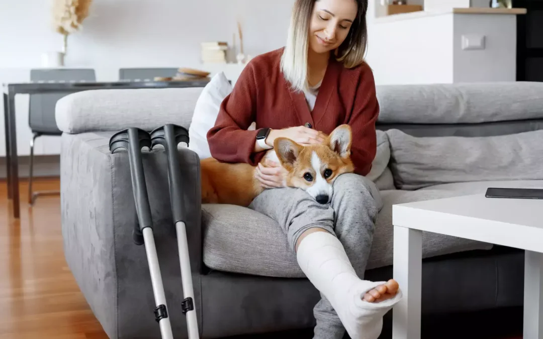 Woman with cast and crutches cuddling dog on couch.