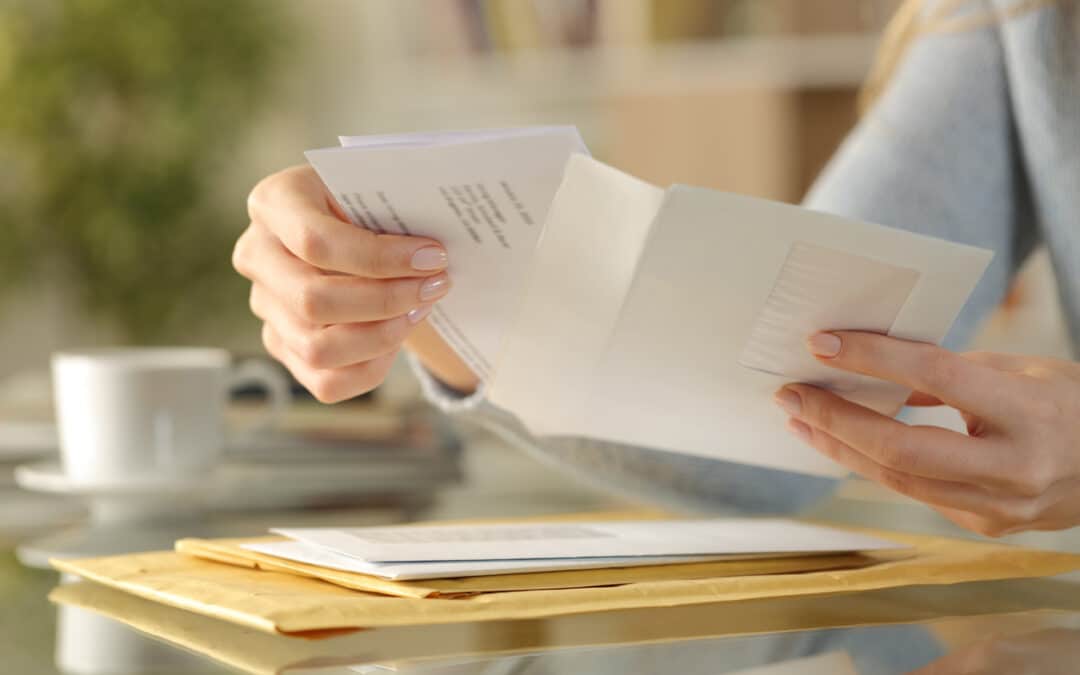 Person opening envelope with letters on table