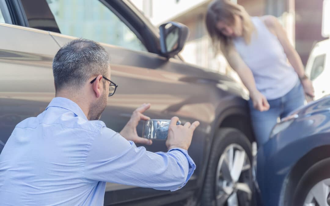 Man photographing car accident damage on phone.