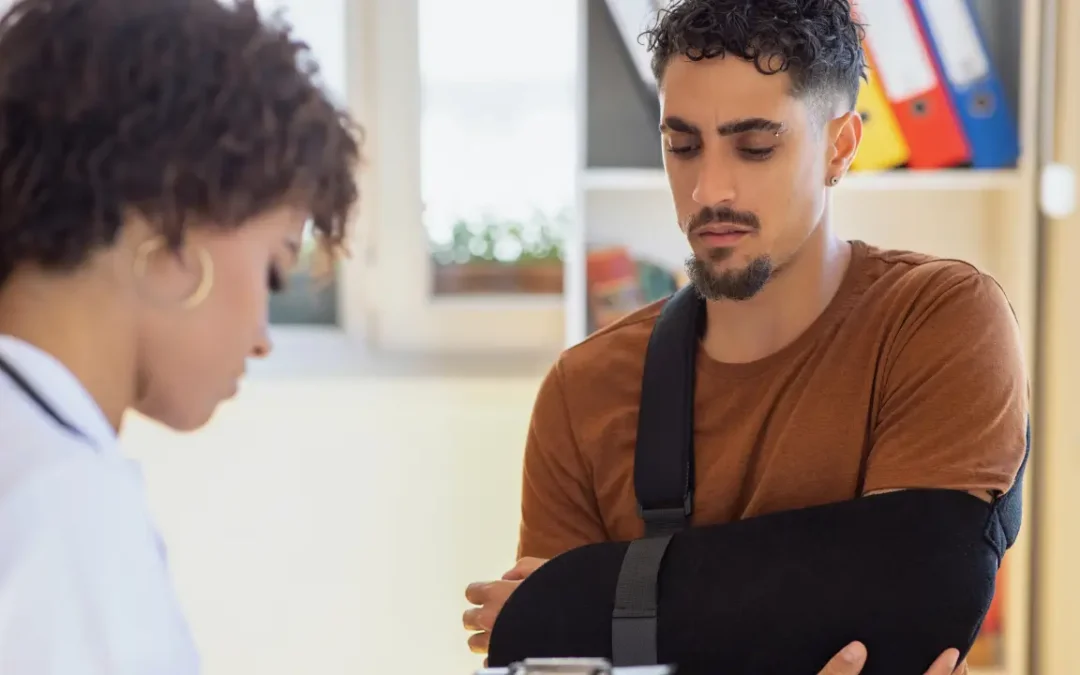 Doctor consulting man with arm in sling