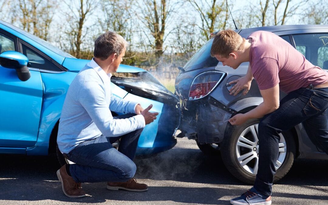 Two men inspecting minor car accident damage.