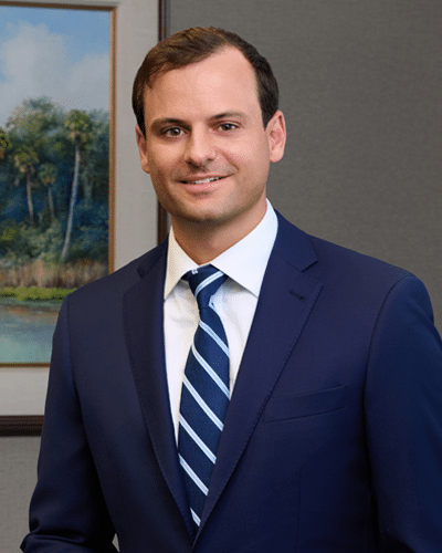 Man in suit standing by landscape painting.